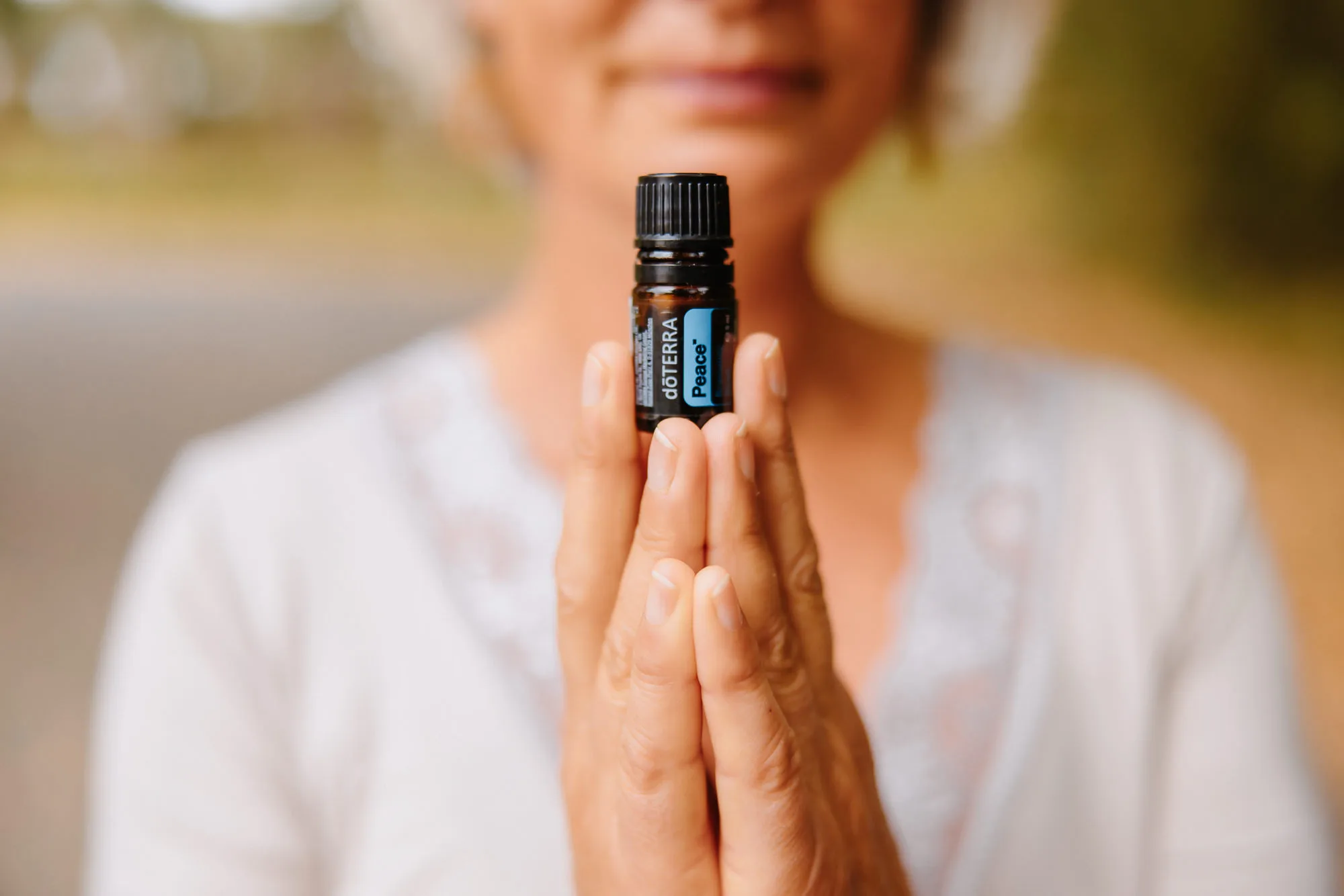 Primer plano de unas manos femeninas con el maravilloso aceite esencial “Peace” de dōTERRA